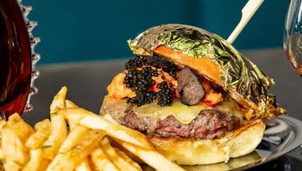 This top-line $700 burger from DBG features n A5 wagyu patty topped with caviar, black truffle and lobster flambéed in a $4800 bottle of Louis XIII cognac.