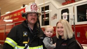 Jon and Nicole Simmons with son JJ, 2, at the Garden City Fire Company station in Wallingford.