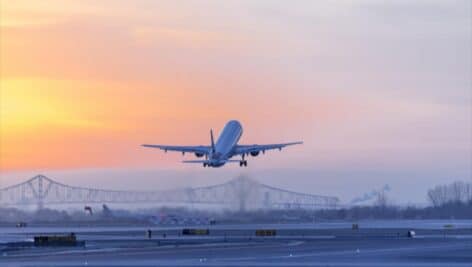 An airline plane lifting off from Philadelphia International Airport around sunset