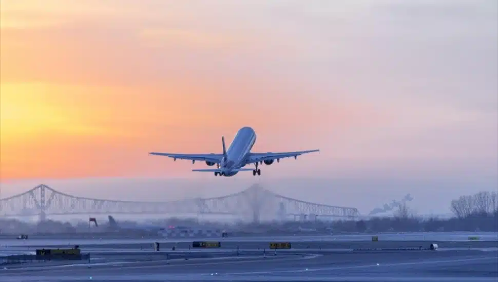 An airline plane lifting off from Philadelphia International Airport around sunset.