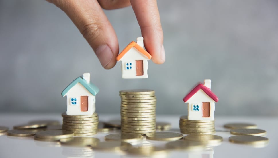Model houses are placed on different stacks of coins denoting their value.