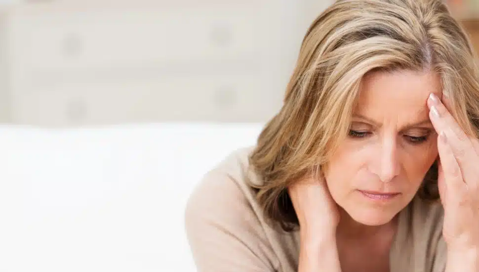 A woman with a hand to her forehead looking stressed