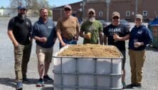 Six brewers behind a container of grains to make this year's Memorial Day beer, "Adapt and Overcome: Get Your Six".