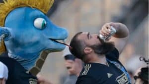 Eagles star Jason Kelce chugged a beer on the field in front of Union mascot Phang (left) .