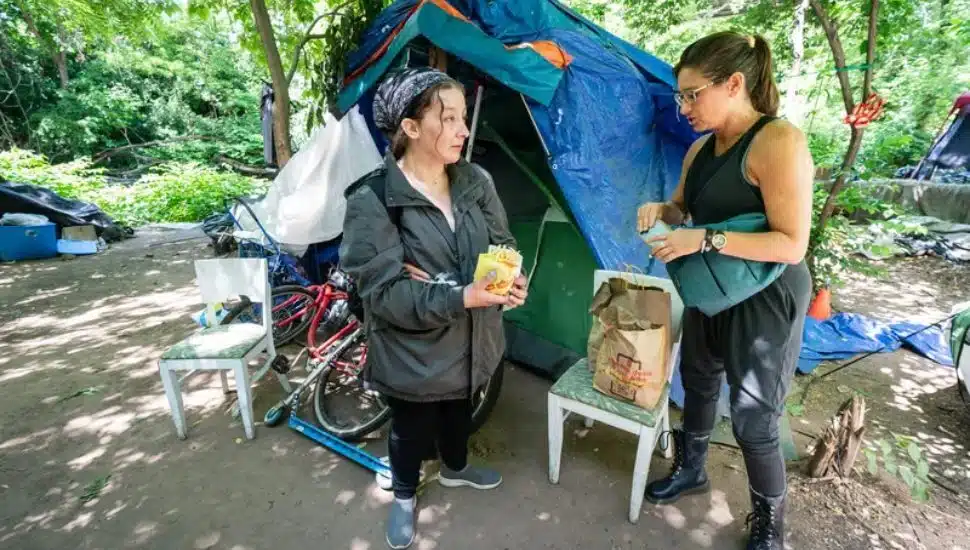 Draya LaMacchia (left) speaks with homeless advocate Sephanie Sena at a homeless encampment in Norristown.