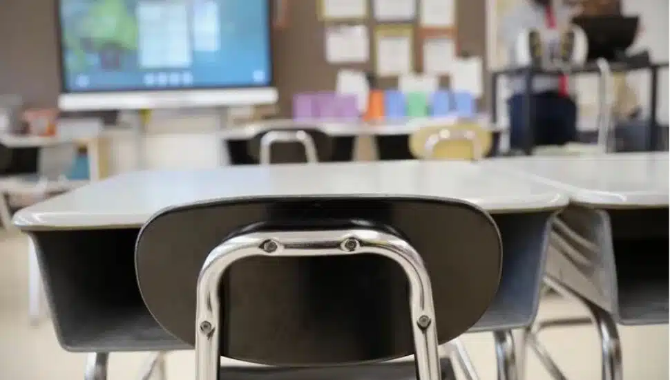 An empty school desk in a classroom.