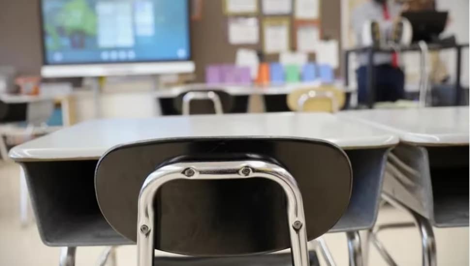 An empty school desk in a classroom.