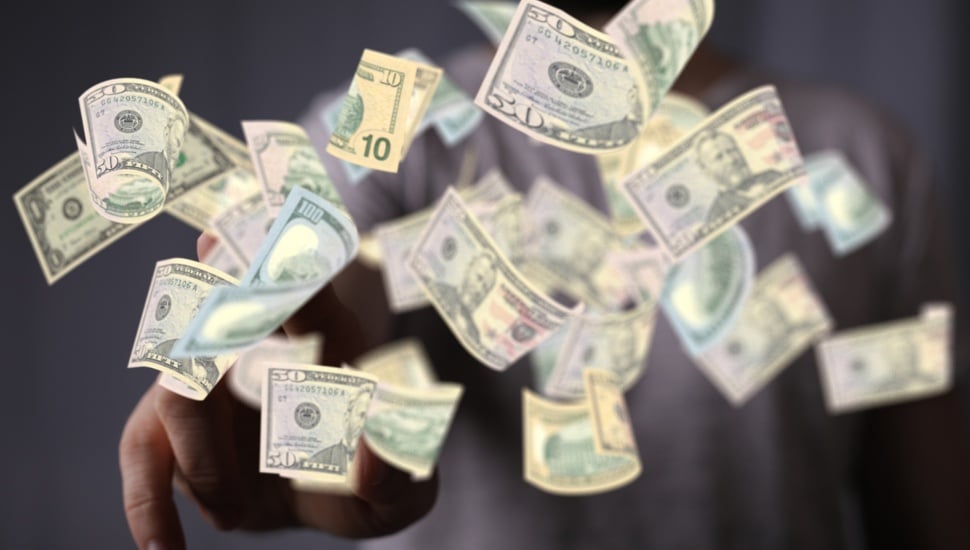 Cash with different denominations falling through the air.