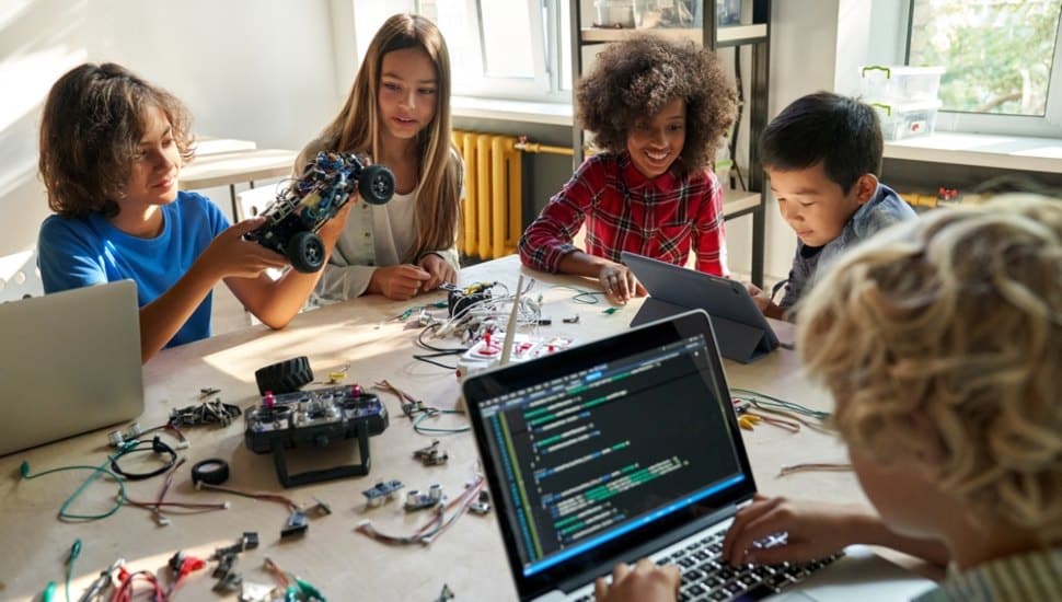 Students are at a table loaded with electronics working on a science project.