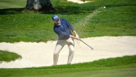 A golfer trying to get his ball out of a sand trap