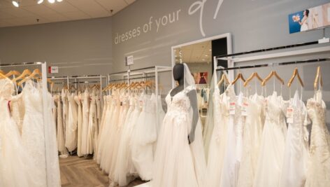 Several rows of wedding gowns hanging in a David's Bridal store