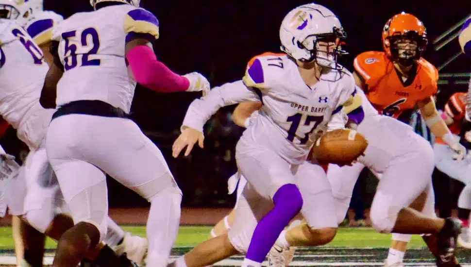 Players with the Upper Darby Royals High School varsity football are playing a game on the field.