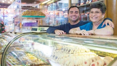A smiling man and woman behind a bakery counter.