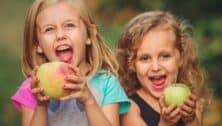 2 kids holding large apples.
