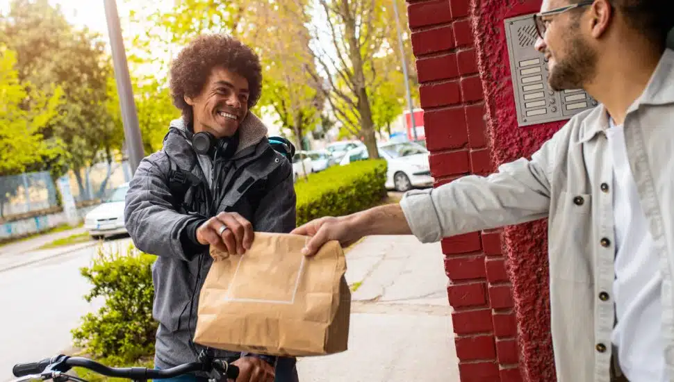 A customer receiving a food delivery from a courier.