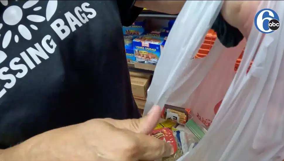 volunteer placing snacks into bag for children at norwood's st stephens church
