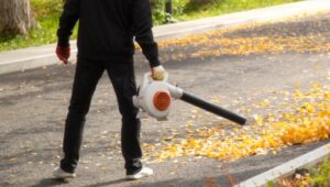 A man uses a gas-powered leaf blower.