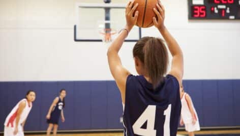 A high school girl basketball player is about to shoot the ball.
