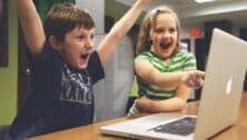 A boy and girl student at the computer are excited by what they see on the screen.