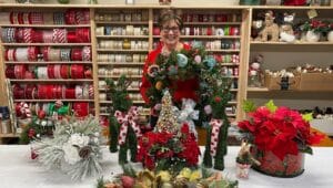 Dunwoody resident, Fran Northrup, shows some of the many floral arrangements created by the Floral Committee, whose work will be showcased and available for purchase at Dunwoody Village’s Holiday Bazaar.