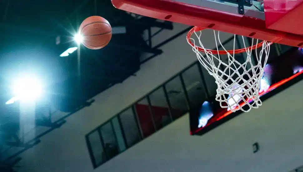 A basketball on its way through the hoop and net.