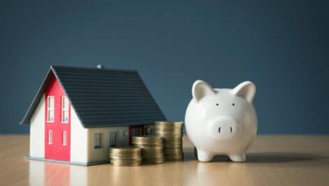 A piggy bank, coins and a model home, symbolically showing the value of a home