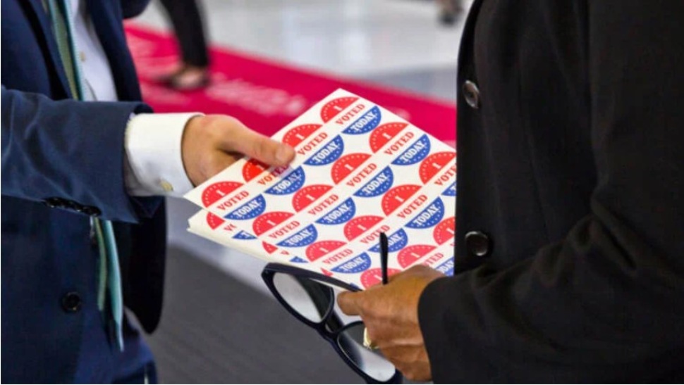 An election worker holds “I Voted” stickers.
