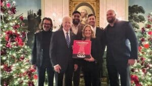 President Joe Biden and Dr. Jill Biden hold the Philadelphia Eagles Christmas album, 'A Philly Special Christmas Special', surrounded by members of the Eagles team.