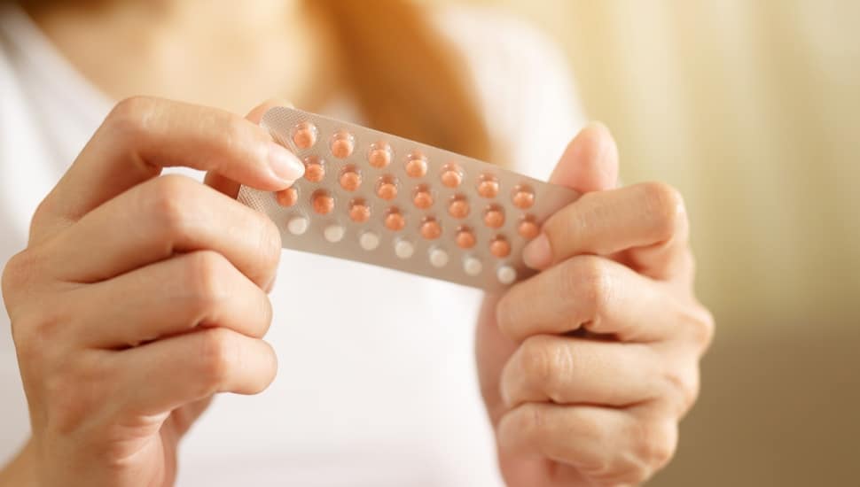 A woman holds a packet of birth control pills.