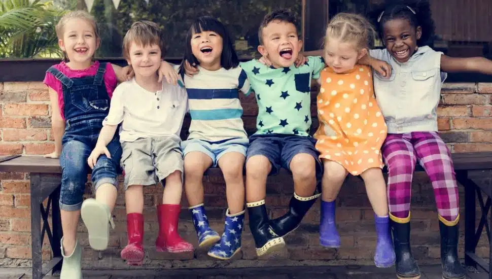 Six happy children sitting in a row, smiling and laughing.