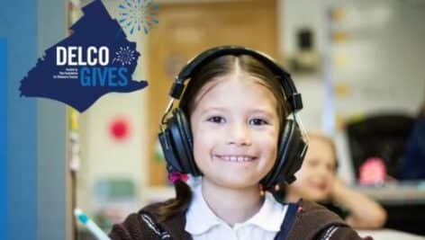 A happy child wearing headphones with a Delco Gives icon to her left.