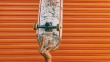 A piece of art work showing a hand holding a decorated skateboard.