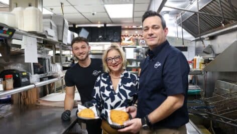 Chancellor Marilyn Wells (center) standing with Epic Double Decker's Ted Kardon (right) and Spiro Karalis (left) after making inside-outs, one of the restaurant's signature dishes.