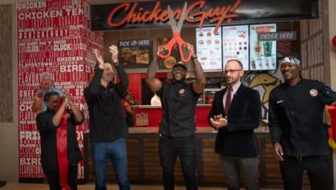 Chicken Guy! owner/operator Kevin Cooper cuts the ribbon Thursday on the new Chicken Guy! location at King of Prussia Mall. With him to the left is Jason Taliaferro, senior vice president of Chicken Guy! and Todd Putt, to the right, director of marketing for the chain. The others are employees of the store.