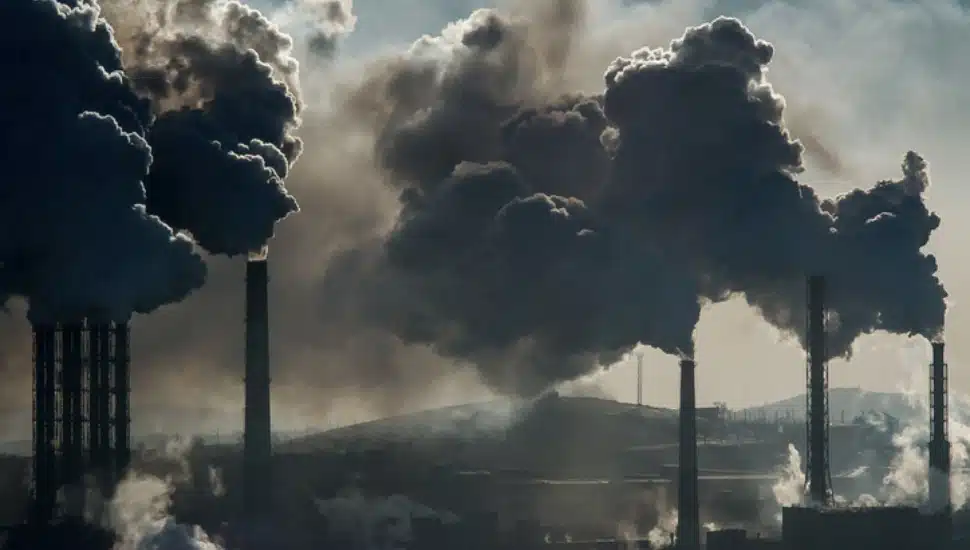 Several factory smokestacks spewing a dark smoke.