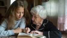 A girl looks over a book with her grandmother.