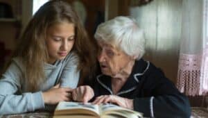 A girl looks over a book with her grandmother.