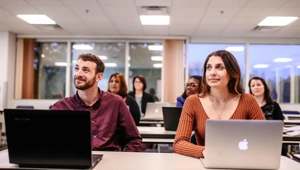 Neumann University students sitting in a classroom in front of laptop computers.