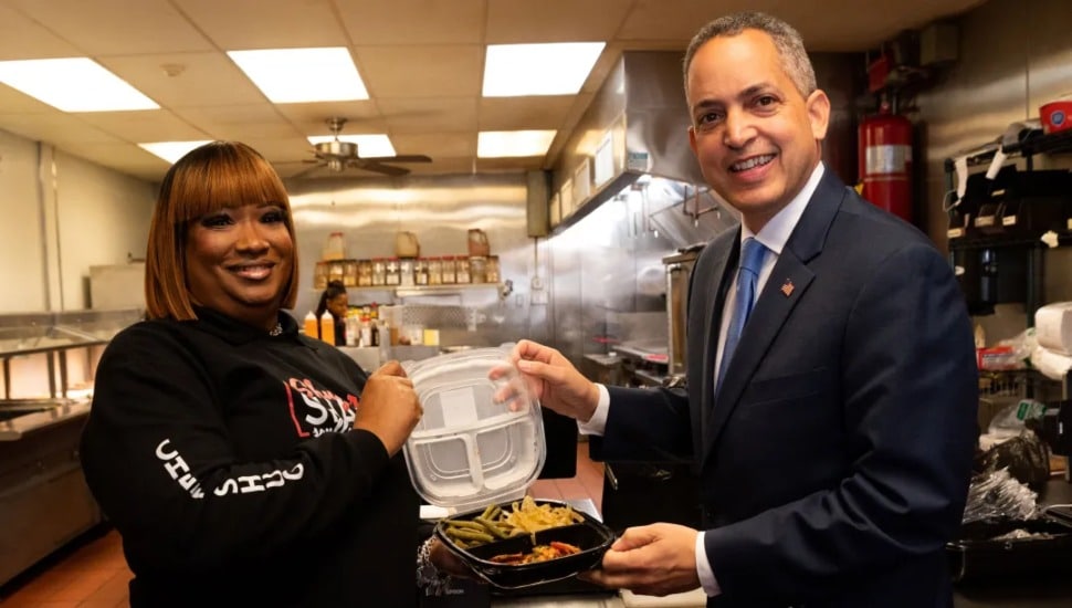 Shugar Shack Soul Food Owner Keenya Cain-Wiggins presents a freshly made takeout order to U.S. Department of Commerce Deputy Secretary Don Graves.