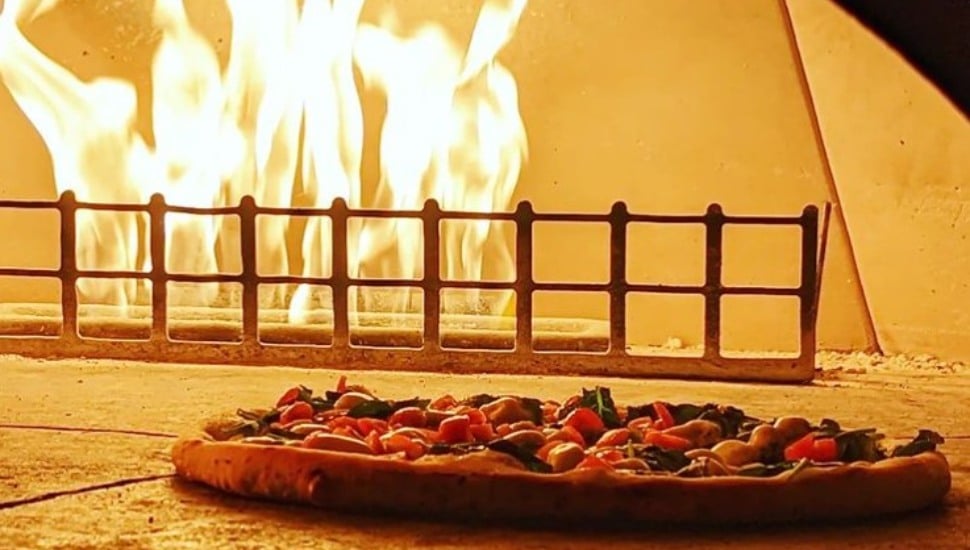 A hand-tossed pizza ready for the wood-fired oven at Tecca Newtown Square.