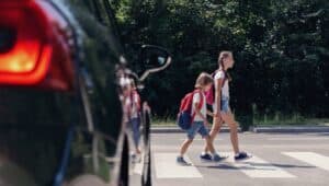A braking car approaches two children walking.