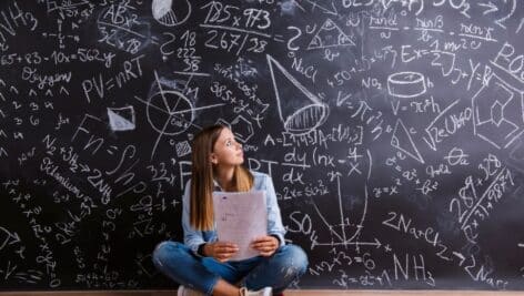 A high school student contemplating a chalk board filled with equations.