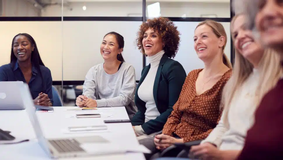 Women in business shown sitting around a conference table.
