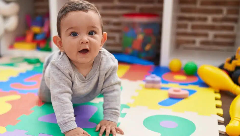 A baby crawls on a blanket.