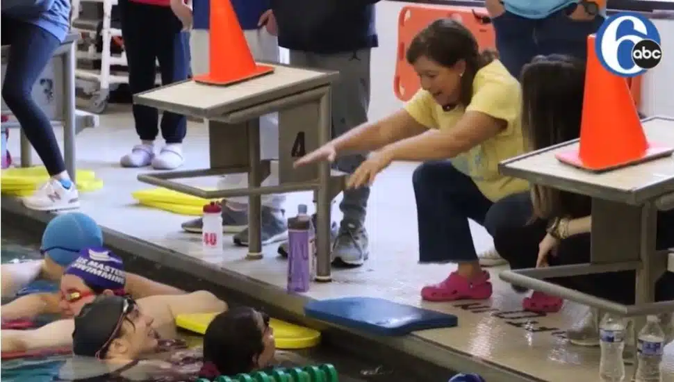 A volunteer coach works with special needs swimmes as they work on skills to compete in the Special Olympics.