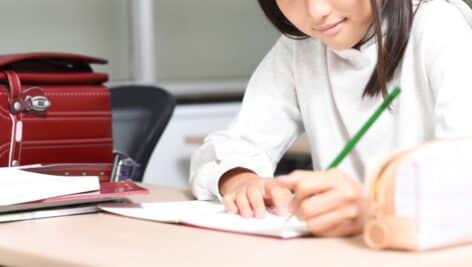 A student writes in a tablet at her school desk.