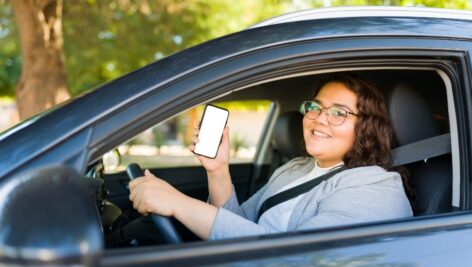 a Young woman food delivery driver holding up her cell phone