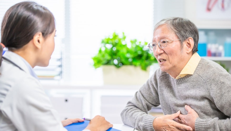 An older man talks with a doctor about his heart symptoms.