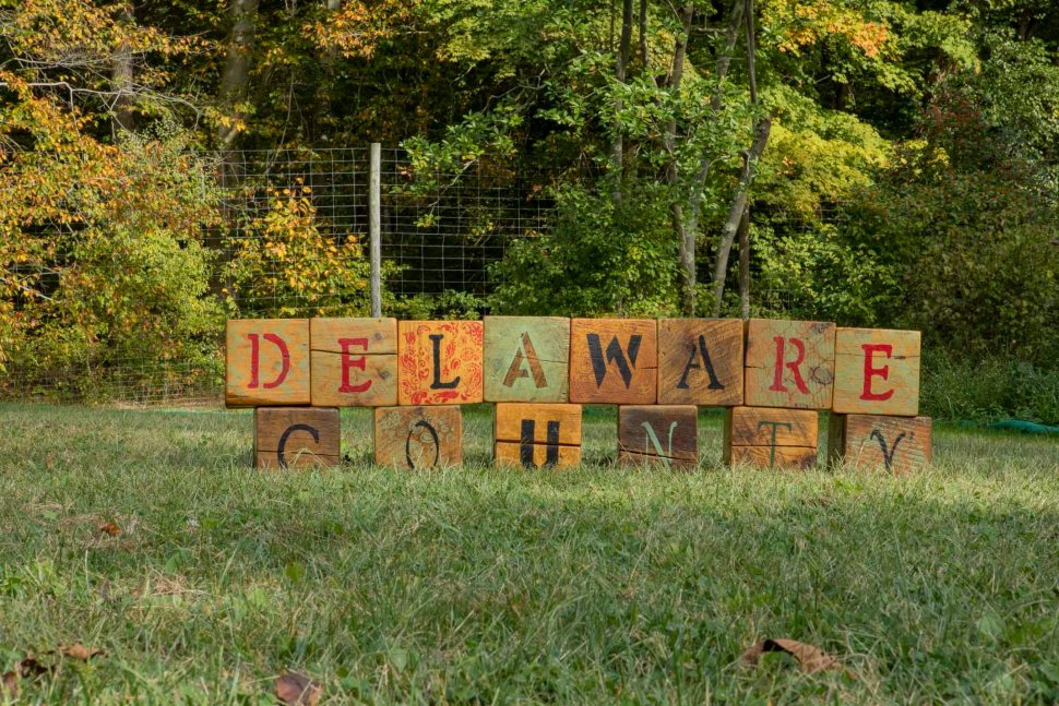 A sign of wooden blocks sitting on a lawn that spells out Delaware County