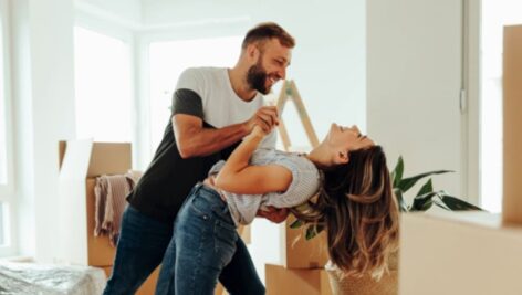 A young couple happy/recently purchased a home with boxes in background.